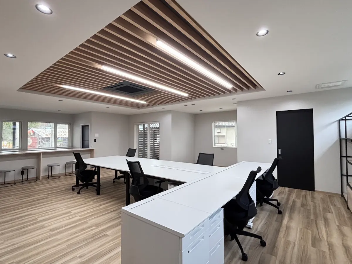 ノリアホームが施工した建設会社の新社屋オフィス。木目天井と白いデスクが並ぶ開放感ある空間