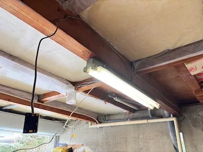 ガレージの天井に露出した配線と照明器具があり、これから板張りで配線を隠すための工事前の状態を写した写真